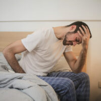 man sitting on bed exhausted
